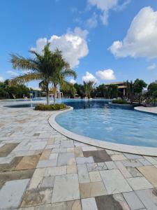 a swimming pool with a palm tree in the middle at ILOA Condomínio Resort Barra de São Miguel in Barra de São Miguel