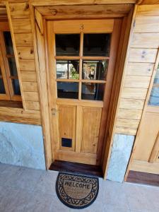 a wooden door with a welcome mat in front of it at Puerto Lacar Lodge SMARG in San Martín de los Andes