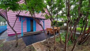 różowo-niebieski dom z ławką przed nim w obiekcie Różana Karczma w mieście Kruszyn