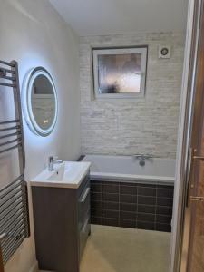 a bathroom with a sink and a tub and a mirror at Cosy Nite B&B in Birmingham