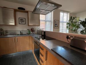 a kitchen with wooden cabinets and a counter top at Beautiful Loft City Centre, Liverpool 1 in Liverpool
