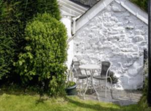 un patio con mesa y sillas junto a una pared de piedra en Cosy Cottage Real Fire Nearby Pub Garden Parking en Altarnun