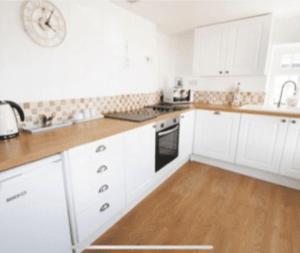 una cucina con mobili bianchi e pavimento in legno di Cosy Cottage Real Fire Nearby Pub Garden Parking ad Altarnun