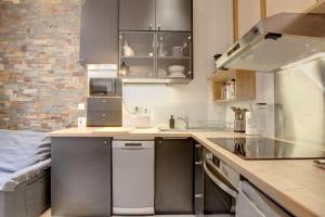 a kitchen with stainless steel appliances and a brick wall at Le Rousseau - Beautiful studio in Old Town in Annecy