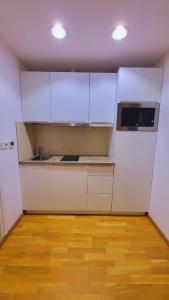 uma cozinha com armários brancos e piso em madeira em Garsoniera în centrul orașului vis a vis de hotel radisson em Bucareste