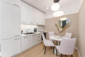 a kitchen with white cabinets and a table and chairs at Aqua Polanki Bodnar Apartments in Kołobrzeg