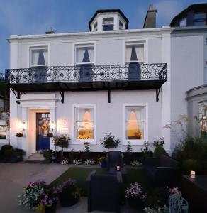 a white house with a balcony on top of it at Highlander House B&B in Rothesay