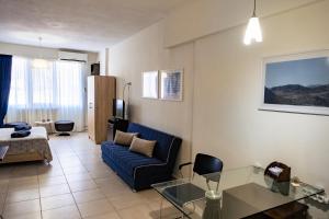 un soggiorno con divano blu e tavolo di PARASIOU STUDIOS 107 διαμερίσματα στο κέντρο της πόλης a Komotini