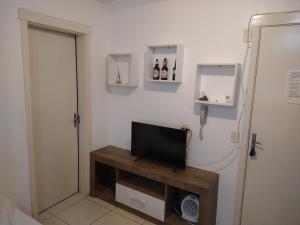 a room with a television on a table and a door at Apartamento Aconchego in Bento Gonçalves