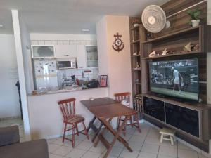 eine Küche mit einem Tisch und einem TV im Zimmer in der Unterkunft HELBOR ATLANTIS (PÉ NA AREIA) in Bertioga