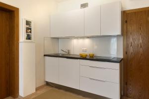 a kitchen with white cabinets and a sink at Appartements Kanauf in Krumpendorf am Wörthersee