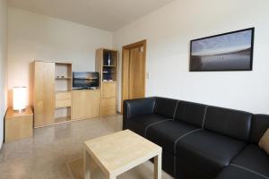 a living room with a black couch and a table at Appartements Kanauf in Krumpendorf am Wörthersee