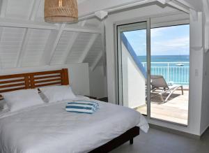 1 Schlafzimmer mit einem Bett und einem Balkon mit einem Stuhl in der Unterkunft Walee Beach Penthouse by the sea, 2 bedrooms, pool in Saint Martin