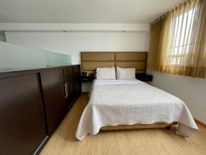 a bedroom with a bed with a white bedspread at My Home Suites in Celaya