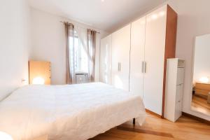 biała sypialnia z dużym łóżkiem i lustrem w obiekcie Sebino Guest House w Mediolanie +10 zdjęć