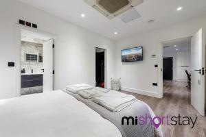 a white bedroom with a large bed and a kitchen at The Residence Fitzrovia - Private One Bedroom Apartment With Own Entrance in London