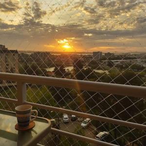 a coffee cup sitting on a balcony with a sunset at Apartamento 1 dormitorio estacionamiento Hermosa vista in Concepción