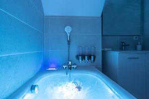 La salle de bains est pourvue d'une baignoire avec un éclairage bleu. dans l'établissement Le Bohème - Spa/Netflix/Wifi Fibre - Séjour Lozère, à Mende