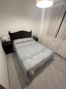 a bedroom with a bed and two tables and a lamp at Adosado Dr Fleming 12 in Poyales del Hoyo