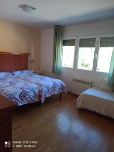 1 dormitorio con 2 camas y 2 ventanas en Casa Las Bailas, en Soria