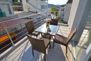 a glass table with chairs and a vase of flowers on a balcony at Apartments Bilanovic in Tisno