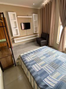 ein Schlafzimmer mit einem Bett, einem Stuhl und einem TV in der Unterkunft Imperial 2 Calçadão in Cornélio Procópio