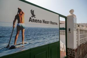 un hombre en una tabla de paddle en el agua en Arena Nest Hostel en Puerto de Santiago