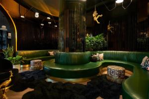 ダラスにあるVirgin Hotels Dallasのリビングルーム(緑のソファ、スツール付)