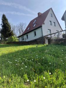 a white house with a field of grass and flowers at Märchenherberge 7 Zwerge in Lichtenau