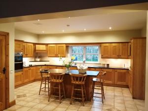 a kitchen with wooden cabinets and a island with bar stools at Rosswood House in Donegal