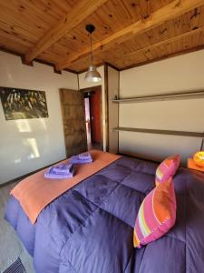 1 cama grande de color púrpura en una habitación con techo de madera. en Girasoles de Valdes en Puerto Pirámides