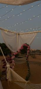 une tente blanche avec des lumières et des fleurs dans le désert dans l'établissement Wahiba Bedouin Rustic Camp, à Muntarib