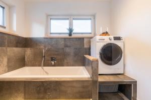 een badkamer met een bad en een wasmachine bij Apartment Waldherz in Wald im Pinzgau