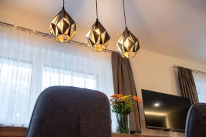 a room with a table with a tv and three lights at Apartment Waldherz in Wald im Pinzgau