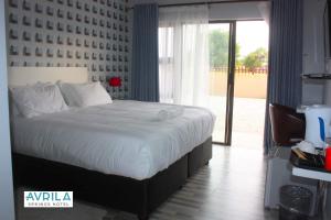 a bedroom with a large bed and a large window at Avrila Springs Hotel in Gaborone +2 photos