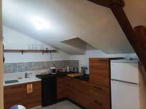 a kitchen with wooden cabinets and a white refrigerator at Studio en pleine campagne avec jardin privatif in Bournand