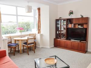 een woonkamer met een tv en een tafel bij Gwylan Apartment in Tenby