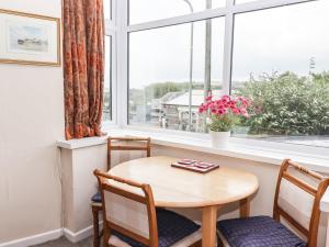 een tafel en stoelen in een kamer met een raam bij Gwylan Apartment in Tenby