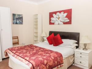 a bedroom with a large bed with red pillows at Gwylan Apartment in Tenby