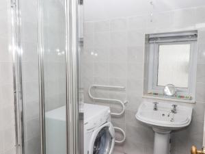 une salle de bain avec une machine à laver et un lavabo dans l'établissement Gwylan Apartment, à Tenby 9 autres photos