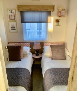 2 camas en una habitación pequeña con ventana en The Wardens Retreat - Tattershall Lakes Country Park, en Tattershall