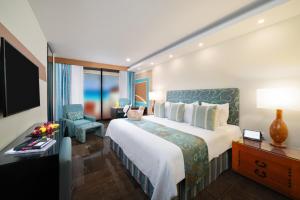 een hotelkamer met een groot bed en een stoel bij The Pyramid Cancun by Oasis - All Inclusive in Cancun