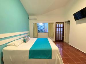 Schlafzimmer mit einem Bett mit blauer Wand in der Unterkunft Calypso Beach Hotel by The Urbn House Santo Domingo Airport in Boca Chica