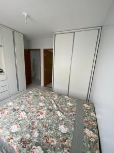 a bedroom with a bed with a floral bedspread at Apartamento no bairro universitário in Caruaru