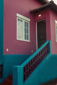 a pink and blue house with a porch at Esquina Brotense_Hospedagem de charme in Brotas