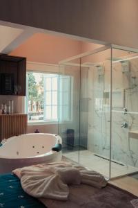 Das Bad ist mit einer Badewanne und einer Glasdusche ausgestattet. in der Unterkunft Esquina Brotense_Hospedagem de charme in Brotas