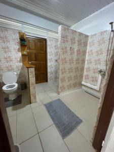 een badkamer met een toilet en een houten deur bij PK 35 in Apomaoro