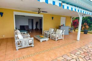 a patio with chairs and a couch and a table at Villa Aloes: Vue mer et calme à 2 pas de la plage in Le Diamant