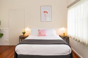 um quarto com uma cama grande com lençóis brancos e almofadas cor-de-rosa em Pacific Motel 02 em Forster