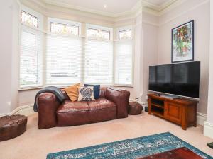 a living room with a leather couch and a flat screen tv at Yewdale in Lytham St Annes